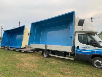 Две синие композитные чаши бассейнов на грузовом автомобиле с прицепом